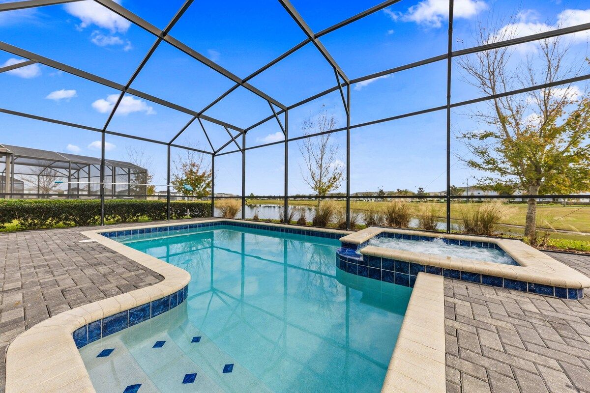 A swimming pool with a glass enclosure, surrounded by a brick patio.