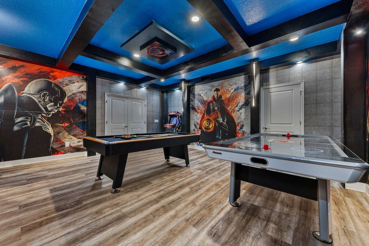 Een biljart tafel, een tafeltennistafel, een plafond met blauwe verlichting, en een muur met een muurschildering.