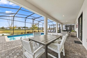 An outdoor patio with a pool, a table, and chairs.