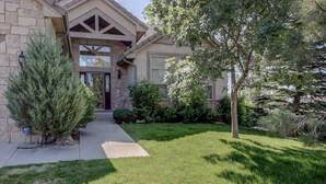 A two-story house with a stone facade, a front porch, and a well-maintained lawn. - Stunning Large Home in Gated Community (Monument)