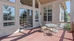 A covered patio with a table and chairs, large windows, and a view of the outdoors. - Stunning Large Home in Gated Community (Monument)