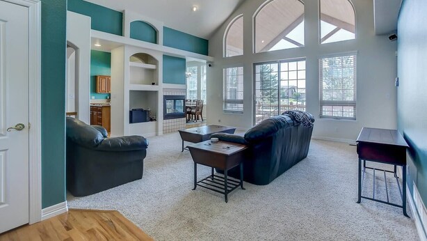 A spacious living area with a fireplace, a dining table, and a large window providing natural light. - Stunning Large Home in Gated Community (Monument)