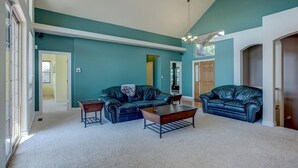 A spacious living room with teal walls, two leather sofas, a coffee table, and a chandelier. - Stunning Large Home in Gated Community (Monument)