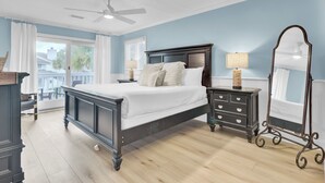 Une chambre avec un grand lit, une commode, un miroir et un ventilateur de plafond.