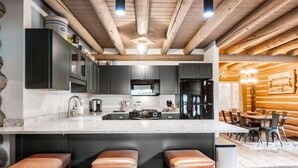 Una cocina moderna con armarios oscuros, una isla grande y taburetes de bar.