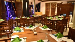 Un comedor con varias mesas dispuestas para el servicio, sillas de madera y un diseño interior moderno.