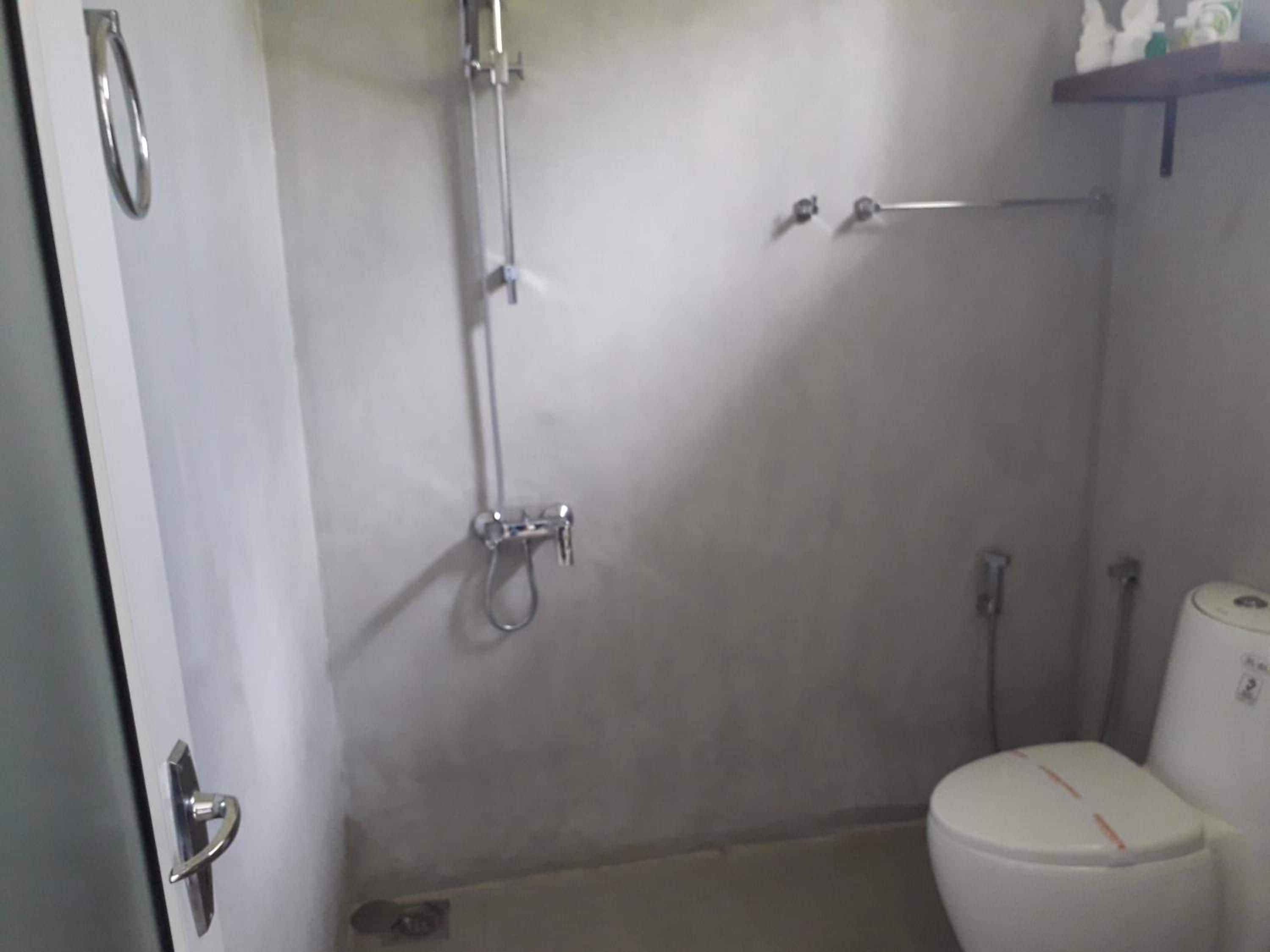 A bathroom with a shower, toilet, and a door with a handle.