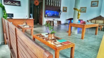 Una habitación con bancos de madera, un televisor y una planta decorativa sobre una mesa.