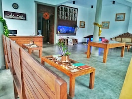Una habitación con bancos de madera, un televisor y una planta decorativa sobre una mesa.