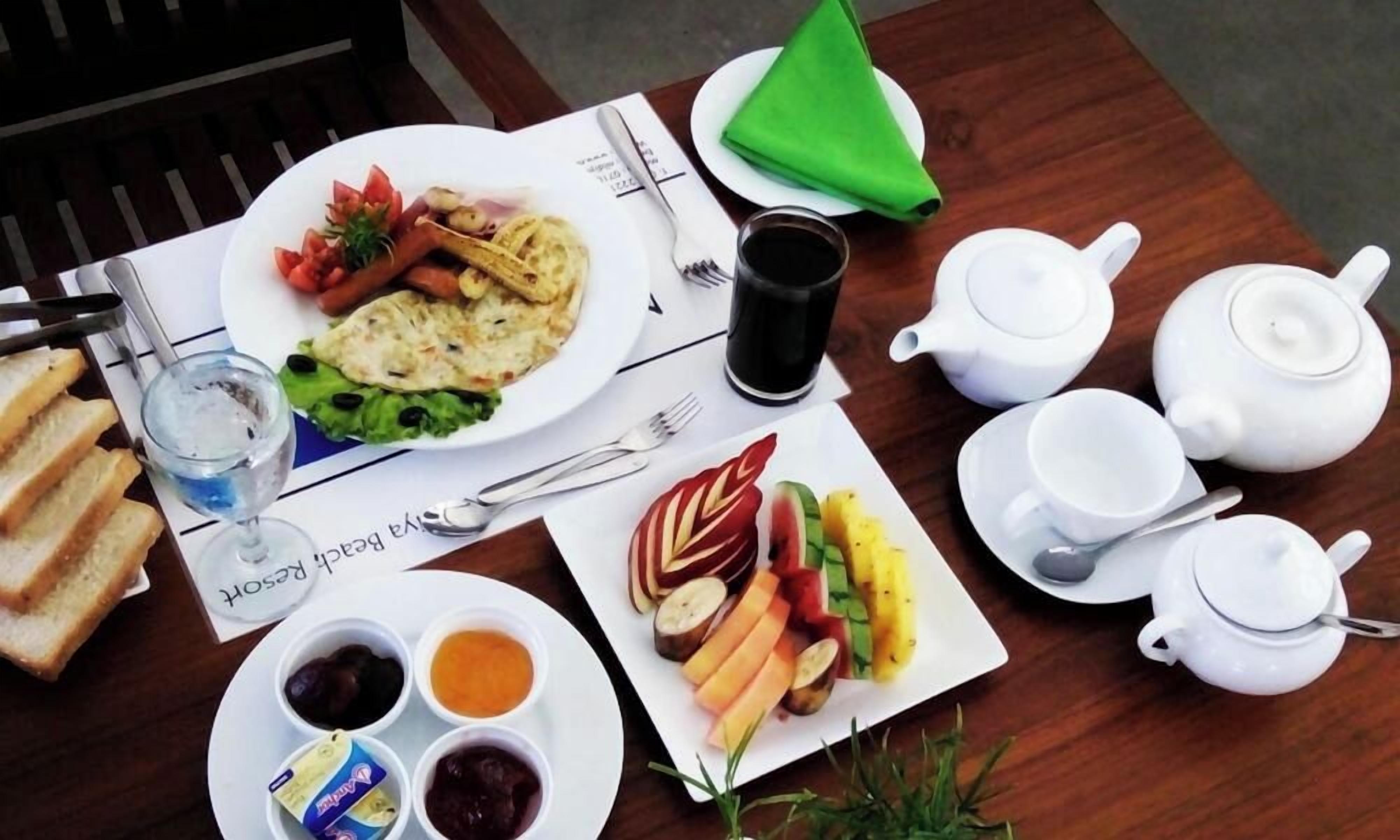 A table set with a plate of food, a glass of water, a teapot, cups, and a napkin.