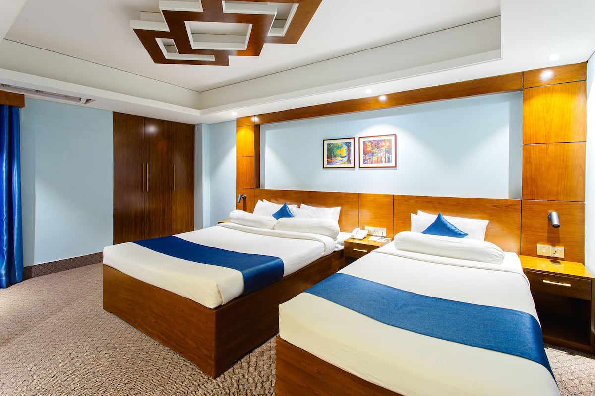 A hotel room with two beds, wooden headboards, a large mirror, and a blue and white color scheme.