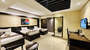 A hotel room with two beds, a desk, a chair, a TV, and a painting on the wall. - Hotel The Capital (Dhaka)