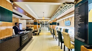A restaurant interior with a long counter, multiple seating areas, and a menu board on the wall. - Hotel The Capital (Dhaka)