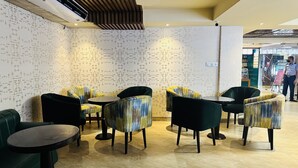 A restaurant interior with patterned wallpaper, modern furniture, and a tiled floor. - Hotel The Capital (Dhaka)