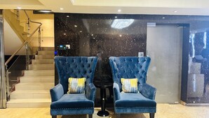 A room with two blue velvet armchairs with yellow and white striped cushions, a small round table, and a black wall with a starry pattern. - Hotel The Capital (Dhaka)