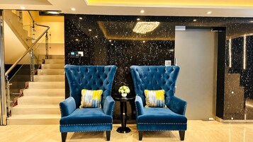 Un vestíbulo con dos sillones azules, una mesita con un florero, y una escalera.