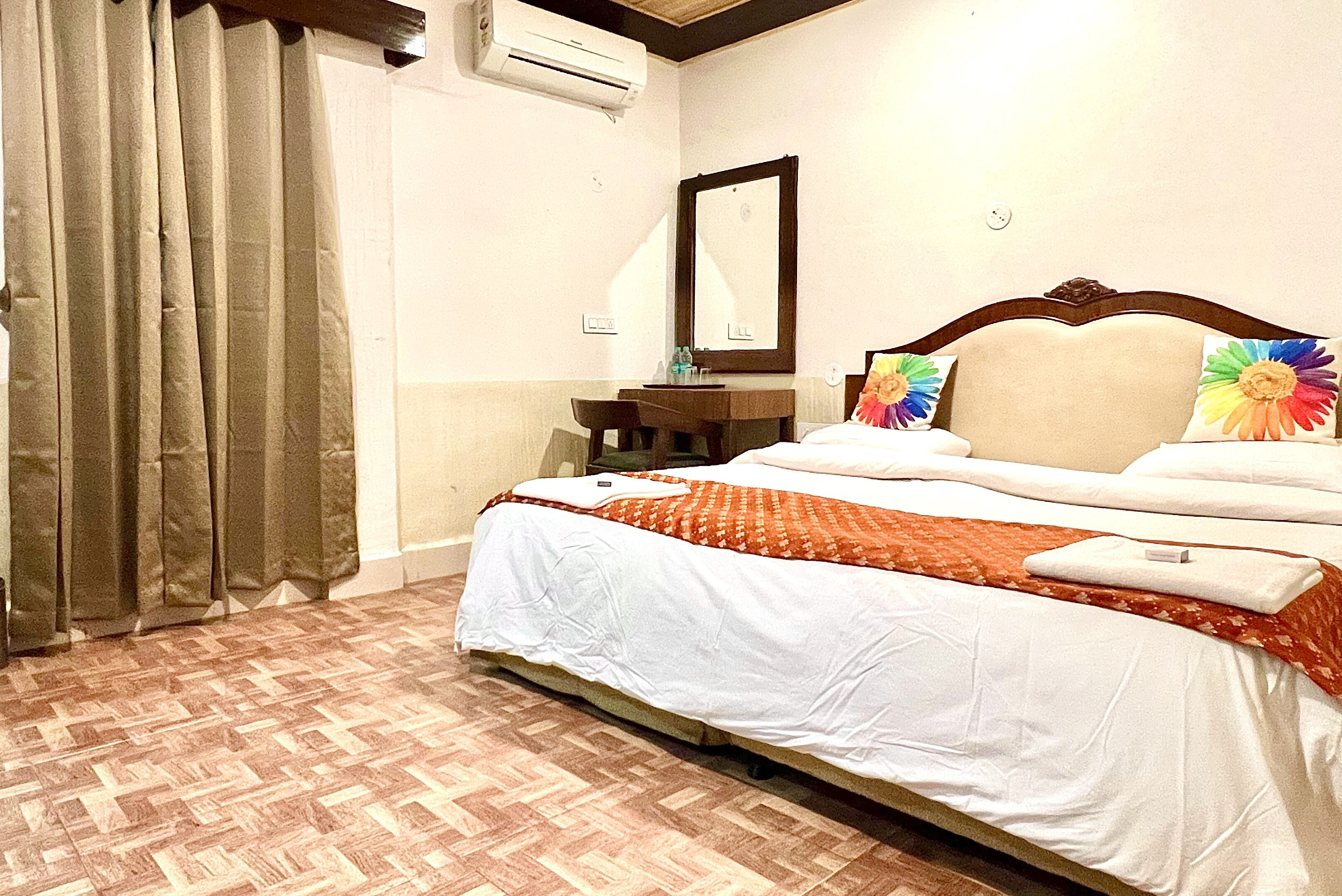 Una habitació d'hotel amb un llit, escriptori, cadira i aire condicionat.