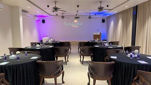 Une salle de conférence équipée de tables rondes, de chaises et d’un pupitre.