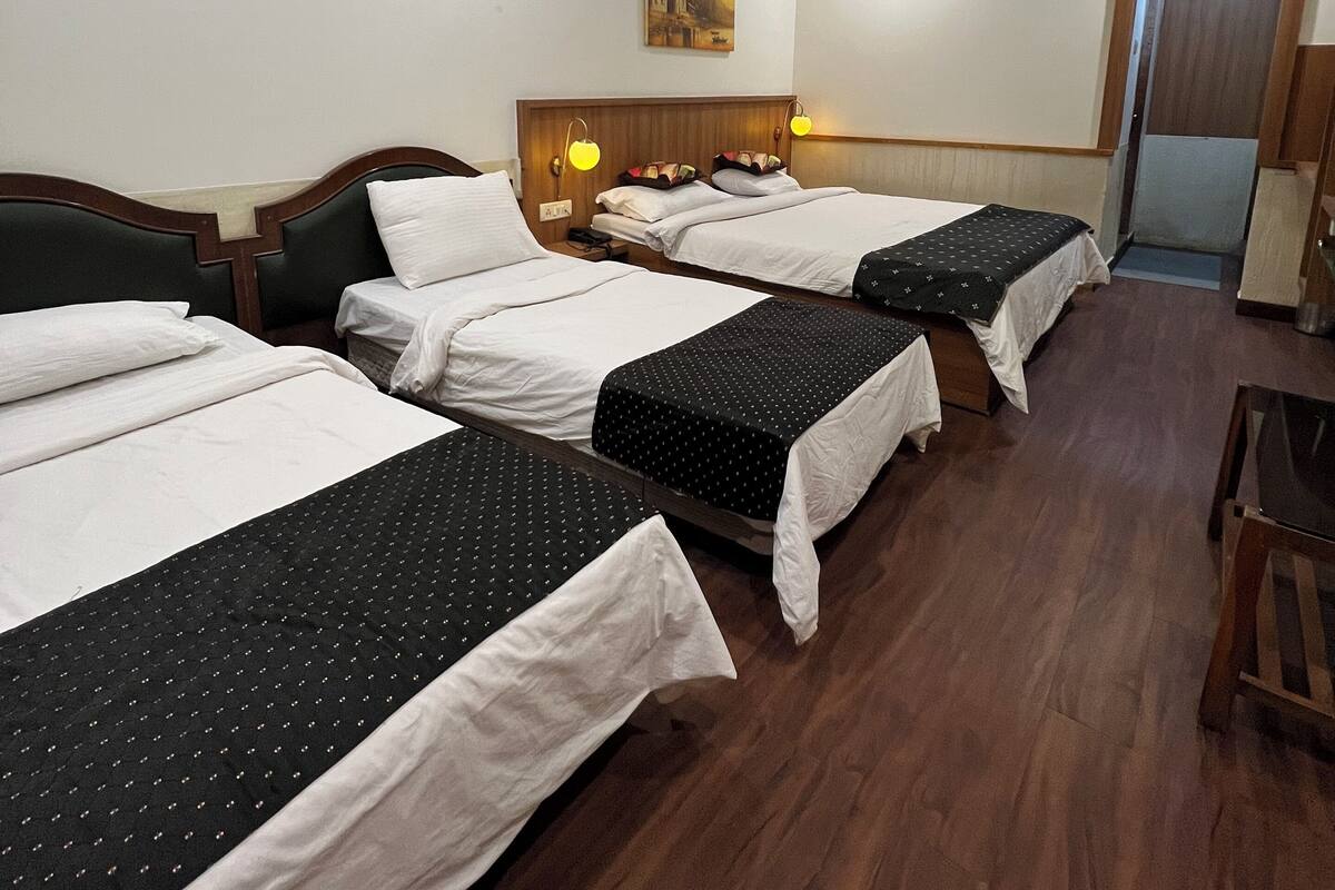 A hotel room with three beds, wooden headboards, and a ceiling fan.