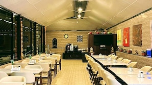 Une salle de conférence avec une longue table, des chaises, un ventilateur de plafond et une horloge au mur.