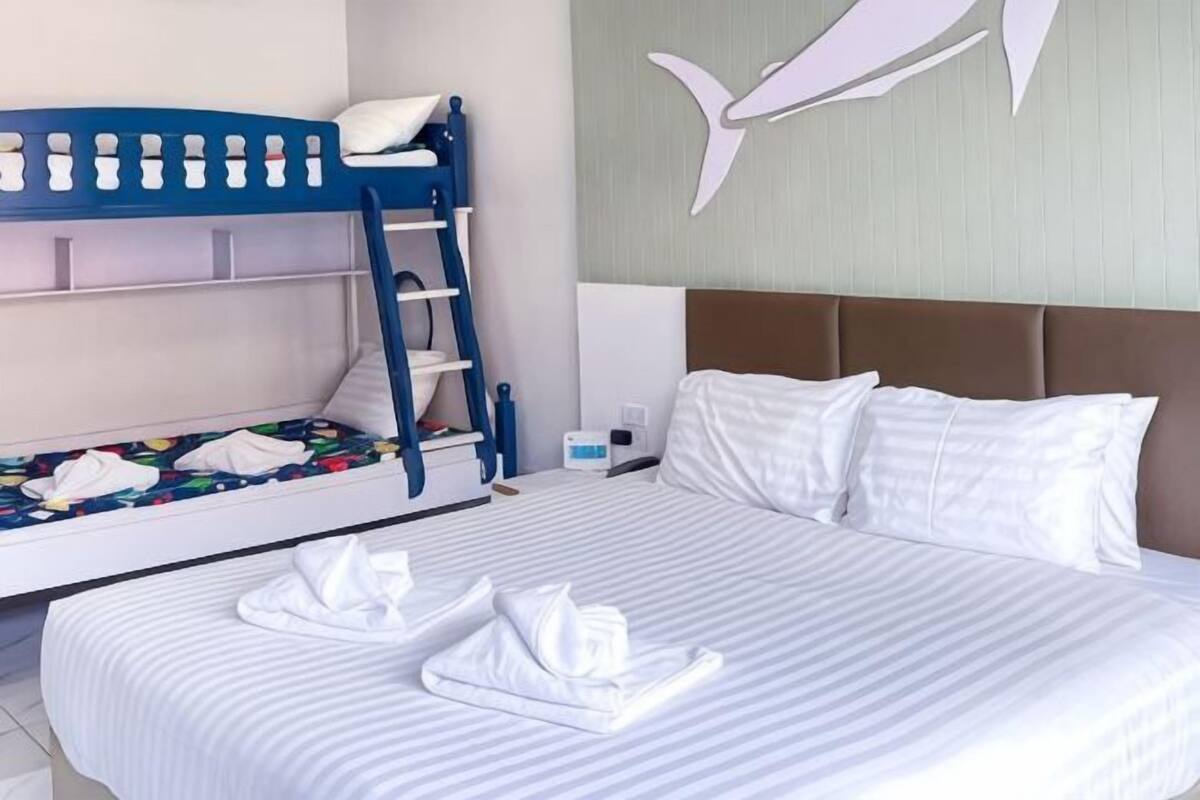A hotel room with a bunk bed, a separate bed, and a wall mural.