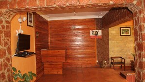A lobby with wooden walls, a reception desk, a television, and a sign. - Saltek Forest cottages (Masindi)