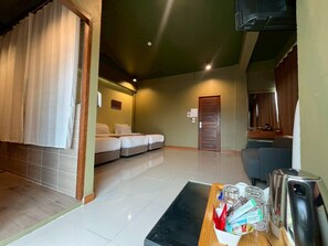 A hotel room with a bed, a desk with a kettle, and a chair. - Work Den Chiangrai (Chiang Rai)