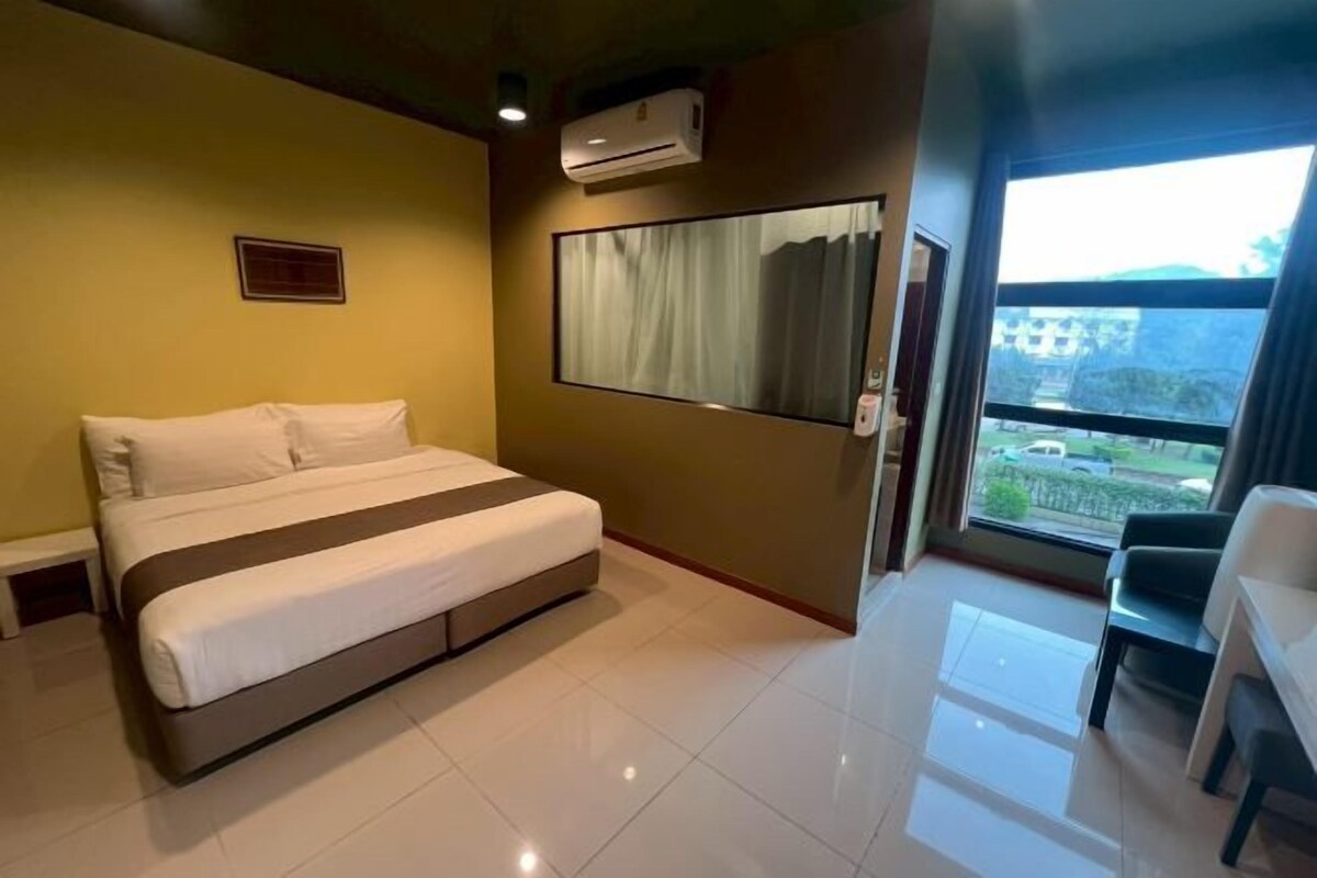 A hotel room with a bed, a window with curtains, a chair, and a view of the outside.