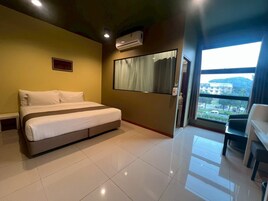 Una habitación de hotel con una cama, un ventanal y vistas a edificios.