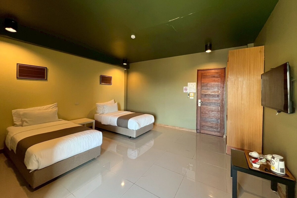 A hotel room with two beds, a small table with a tray, a television, and a door.