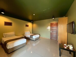 Una habitación de hotel con dos camas, una mesita con bandeja, televisión y una puerta.