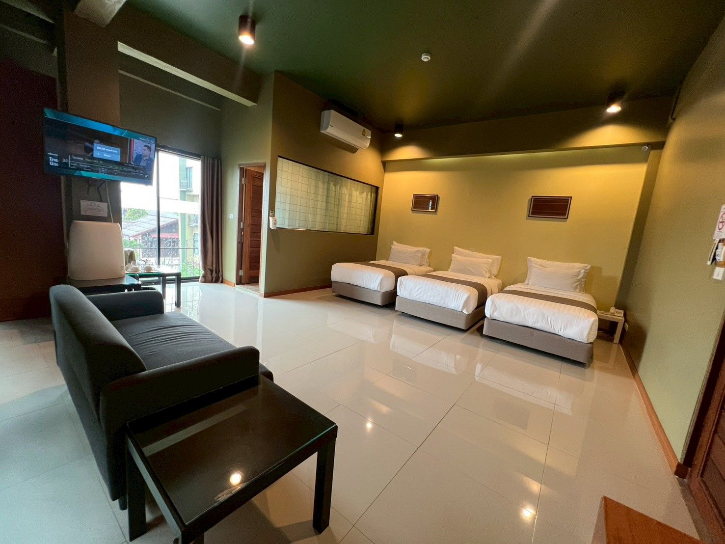 A hotel room with a bed, a sofa, a TV, and a window.