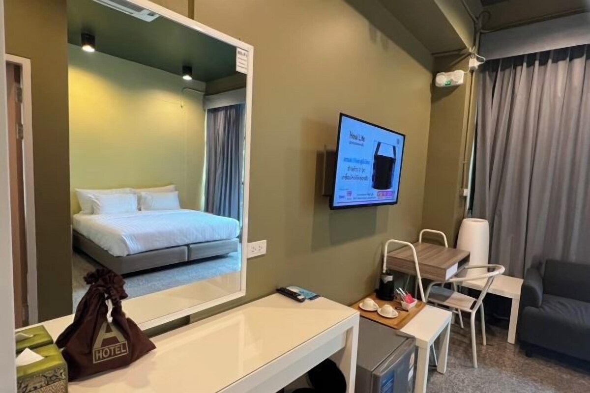 A hotel room with a bed, a desk, a chair, a television, and a window with curtains.