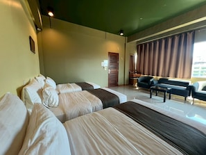 Habitación de hotel con dos camas, un sofá, un escritorio y una ventana con cortinas.