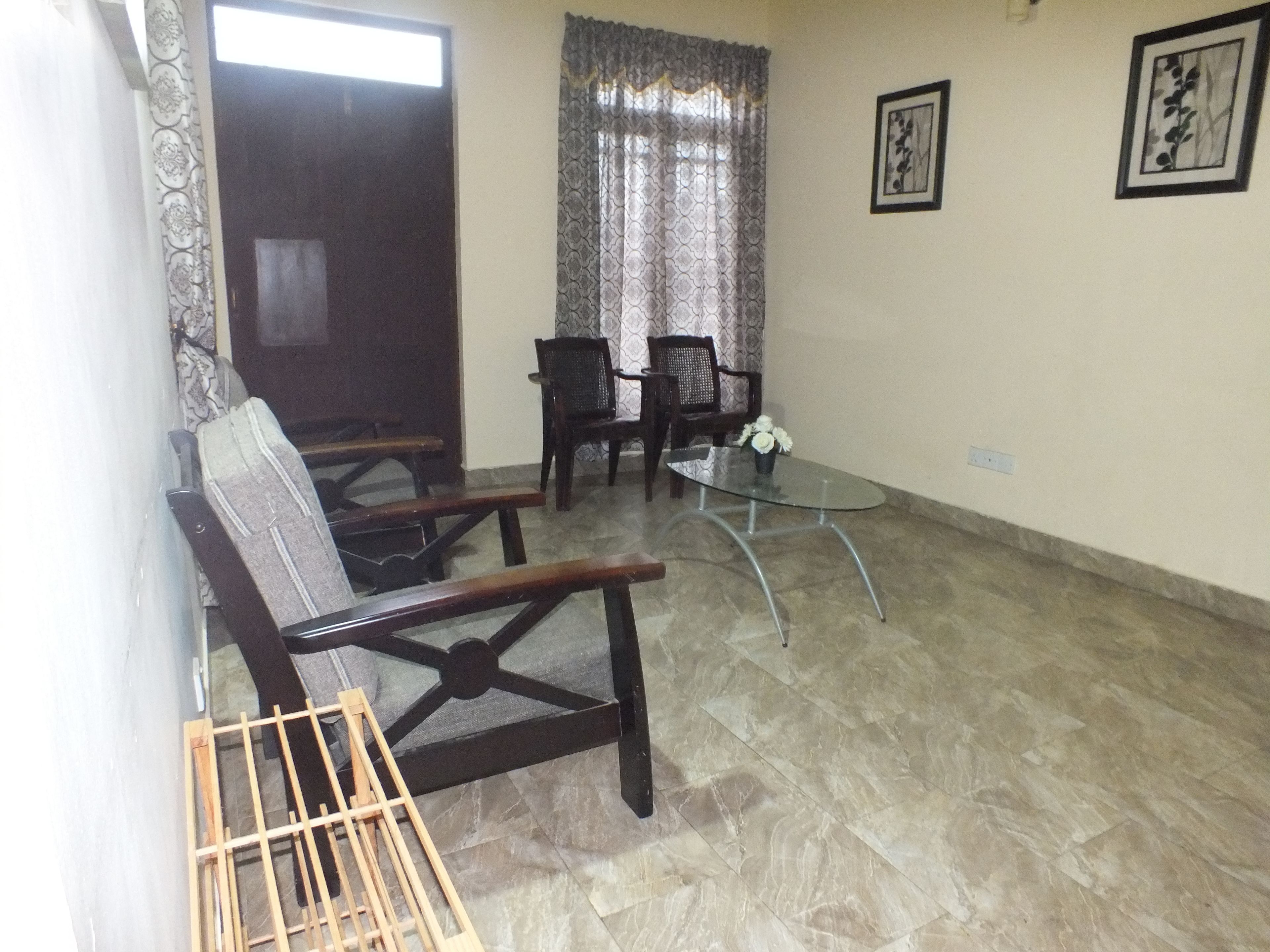 A living room with a sofa, two armchairs, a glass coffee table, and a decorative vase.