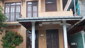 A two-story building with a flat roof, a balcony on the upper floor, and a front door with a sign above it. - Hillsview Rest and Guest House (Matale)
