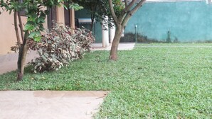 A grassy courtyard with a tiled pathway, a small tree, and a wall. - Hillsview Rest and Guest House (Matale)