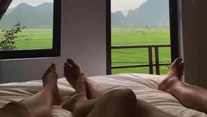 A bed with a view of a green field and mountains through a window. - Hung Phat Bungalow (Phong Nha)