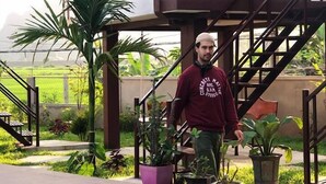 A house with a staircase leading to a balcony, surrounded by potted plants and a swimming pool. - Hung Phat Bungalow (Phong Nha)