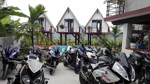 A row of motorcycles parked in front of a building with a white facade and a red roof. - Hung Phat Bungalow (Phong Nha)