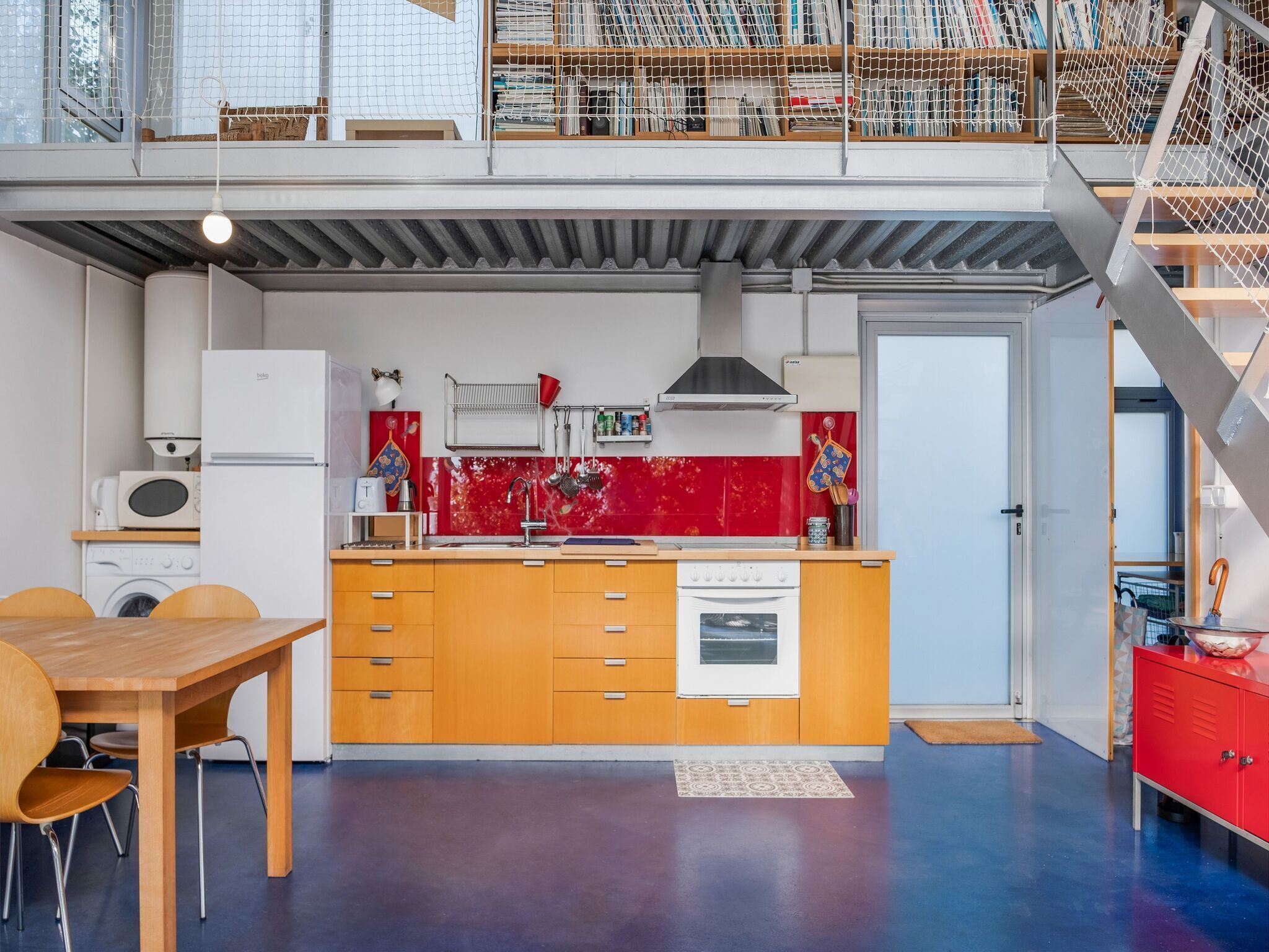 A modern kitchen with wooden cabinets, a red backsplash, and a built-in oven.