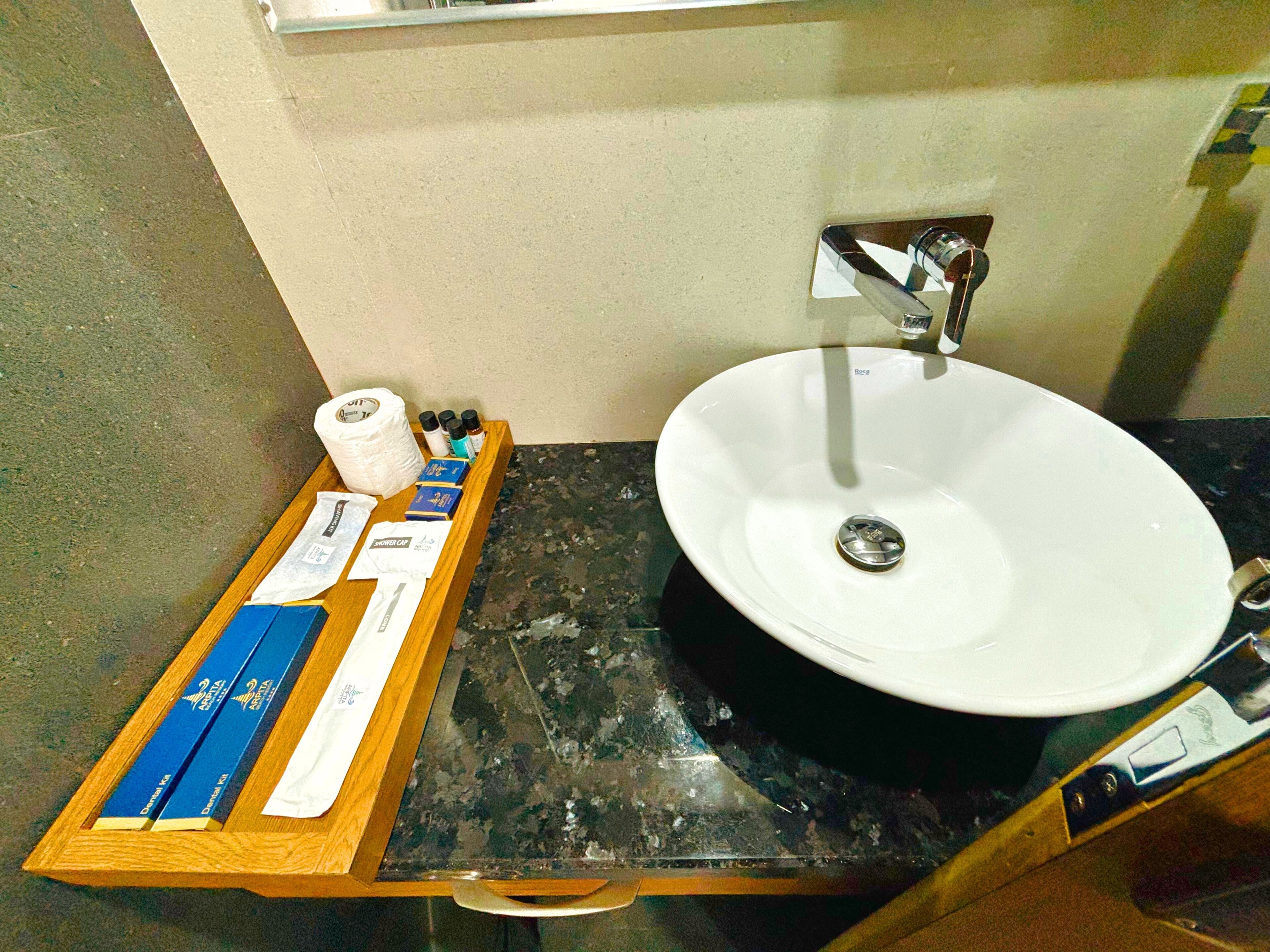 A bathroom with a white sink, a wooden tray with toiletries, and a mirror above the sink.