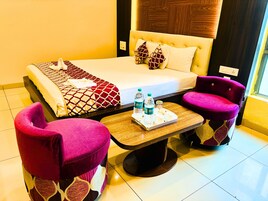 Una habitación de hotel con una cama, dos sillones, una mesita con botellas de agua y una bandeja.