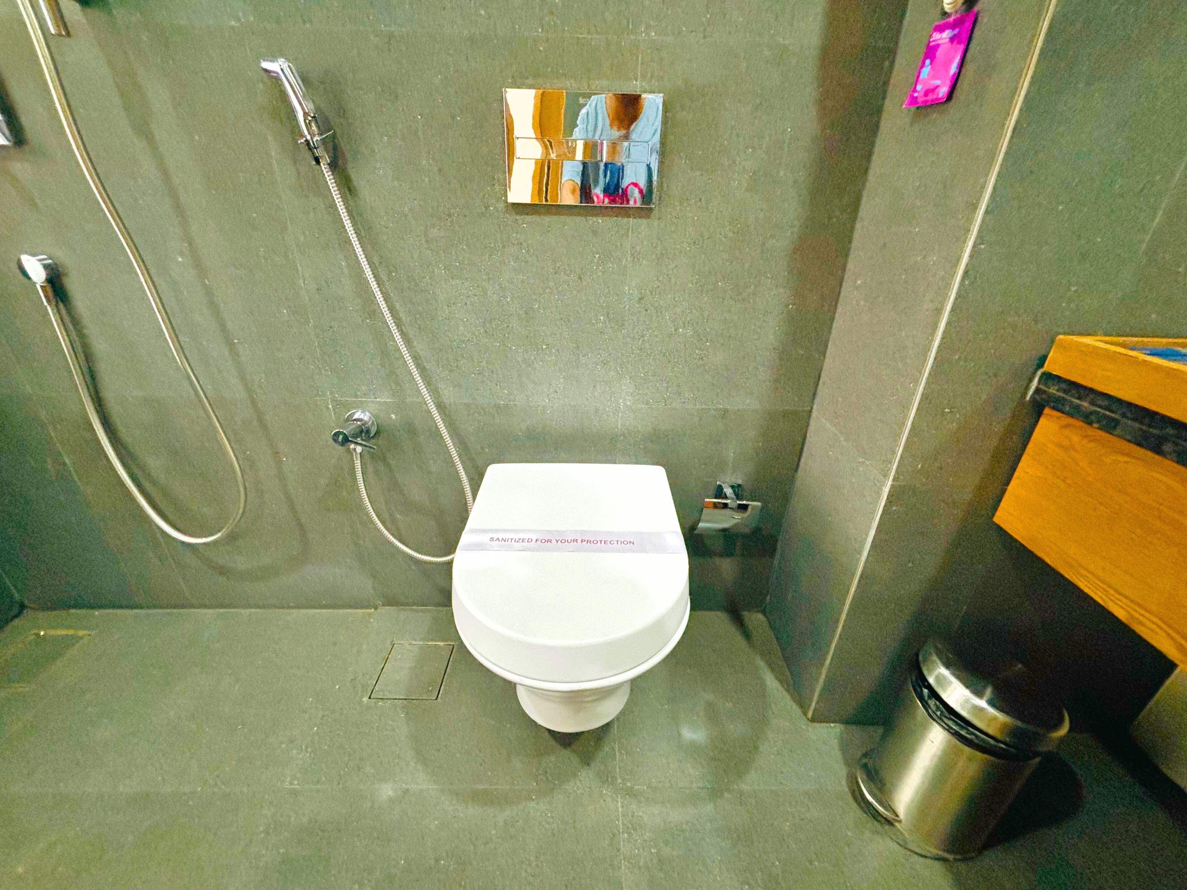 A small, modern bathroom with a white toilet, a shower, and a trash bin.