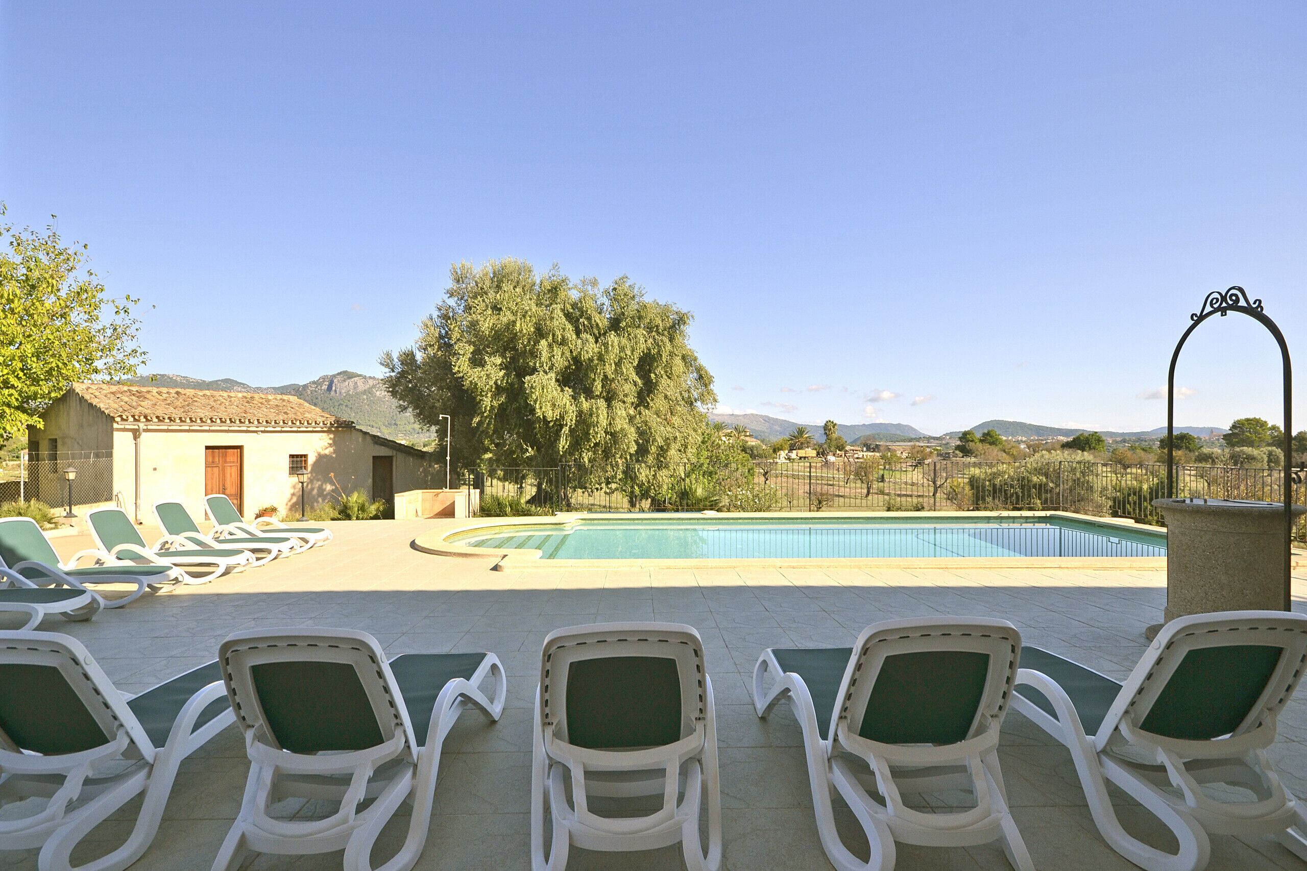 Un área junto a la piscina con sillones de descanso, una piscina y vistas a las montañas.