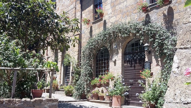 Un patio con paredes de piedra, plantas en macetas y una valla de madera.