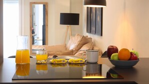 Una mesa de desayuno con una jarra de jugo de naranja, un vaso, un bol de fruta y una taza de café.
