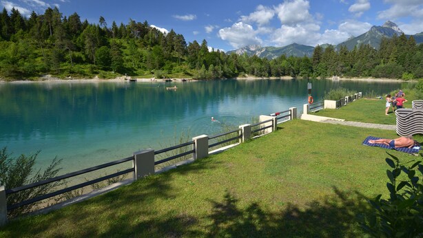 A lake with a wooden deck and a grassy area for sunbathing. - Cozy cottage with large garden, balcony, veranda  (Reutte)