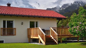 A two-story house with a red-tiled roof, wooden balconies, and a staircase leading to the upper floor. - Cozy cottage with large garden, balcony, veranda  (Reutte)