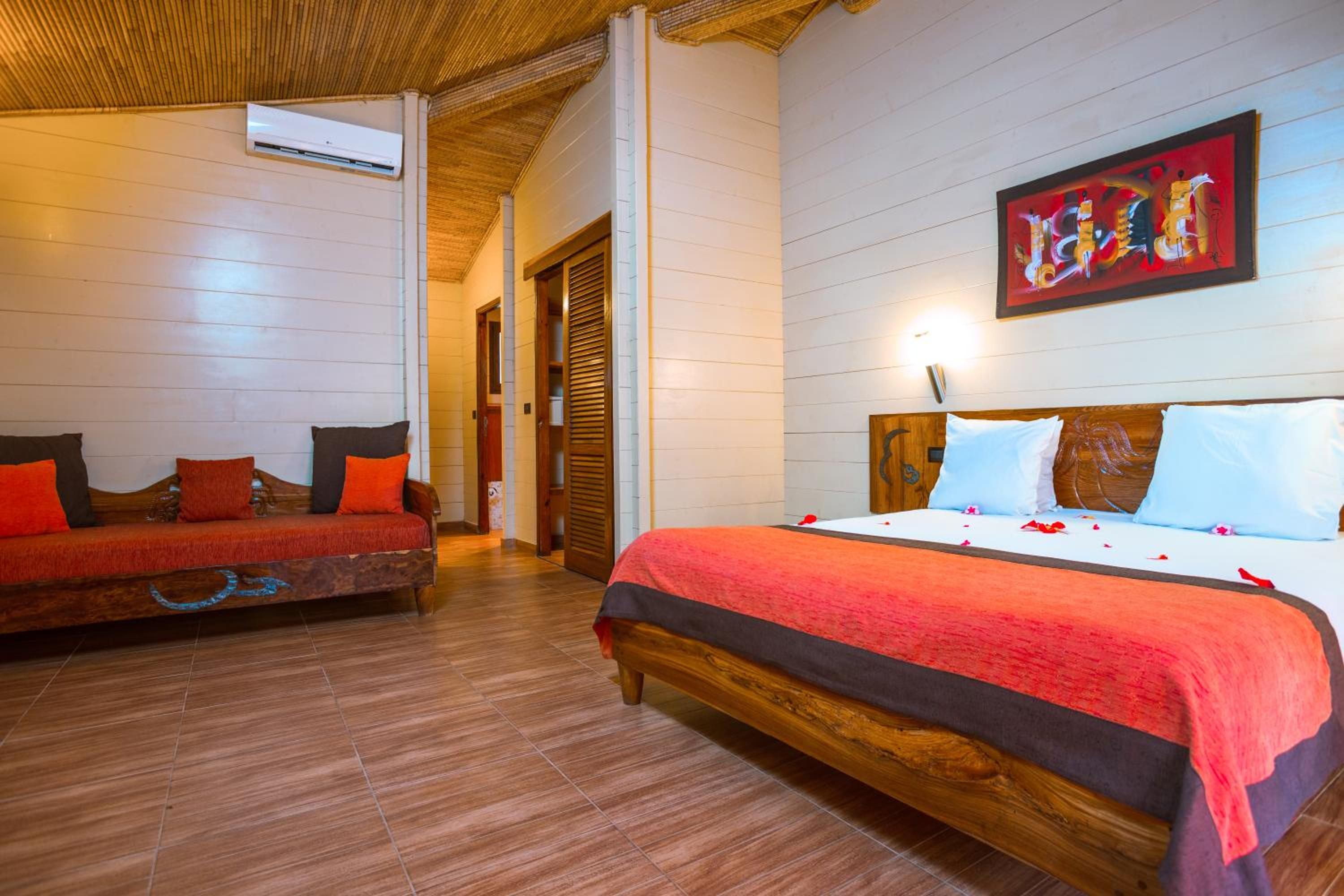 Quarto de hotel com cama de madeira, um sofá e um quadro na parede.
